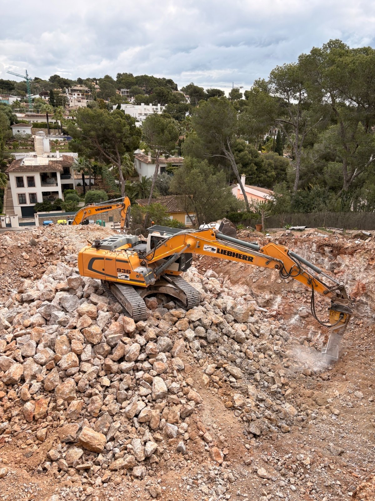 Excavadora con martillo hidráulico en demolición de roca